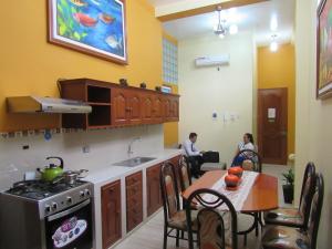 una cocina con fogones y mesa y personas sentadas en una habitación en Alojamiento El Cardenal, en Iquitos