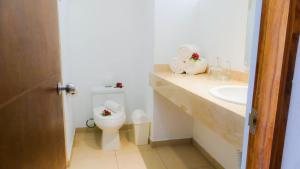 a white bathroom with a toilet and a sink at Casablanca Resort  in Rincon de Guayabitos