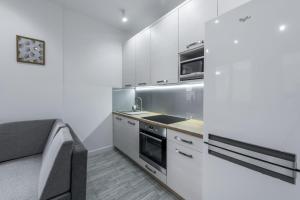 kuchnia z białymi szafkami i kuchenką w obiekcie Apartament Żeglarska U2 w mieście Giżycko