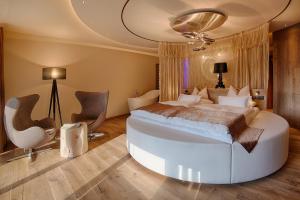a bedroom with a large white bed and chairs at Amonti Wellnessresort in Cadipietra
