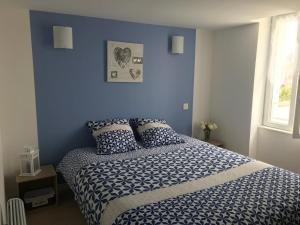 1 dormitorio con paredes azules y 1 cama con almohadas en La Charentaise, en Saint-Palais-sur-Mer
