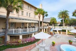杰基尔岛Jekyll Island Club Resort的带有庭院的酒店，庭院内有棕榈树和游泳池