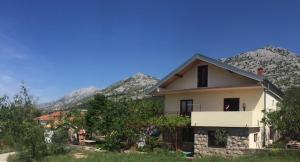 ein Haus mit einem Balkon mit Bergblick im Hintergrund in der Unterkunft Apartments Bili in Starigrad-Paklenica