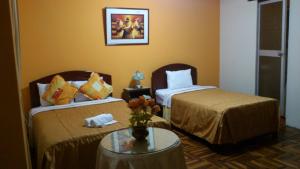 トルヒーリョにあるHotel Plaza Trujilloのベッド2台とテーブルが備わるホテルルームです。