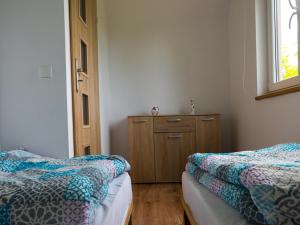 Zełwągi的住宿－Domki letniskowe "Pod lipą"，一间卧室设有两张床、一个梳妆台和窗户。