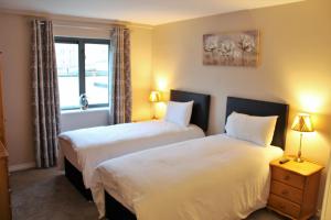2 camas en una habitación con 2 lámparas y una ventana en Wild Atlantic Accommodation 18 Glenveagh Court, en Letterkenny