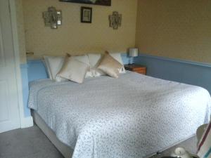 Schlafzimmer mit einem Bett mit weißer Bettwäsche und Kissen in der Unterkunft The Glen Farmhouse in Glenfleak