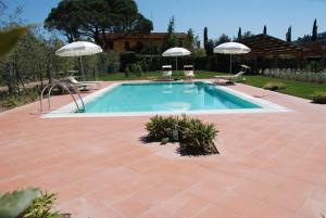 a swimming pool with two umbrellas in a yard at Borgo Piccaratico in Vinci