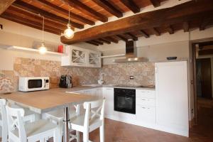 a kitchen with white cabinets and a table with chairs at Mezzanino L Palazzo Gagnoni Grugni in Montepulciano