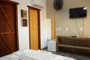 a room with a bed and a tv on the wall at Pousada das Estrelas in Itaúnas