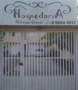 une porte devant un bâtiment avec un panneau dans l'établissement Hospedaria Nossa Casa, à Braço do Norte
