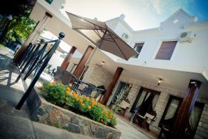 une maison avec une terrasse fleurie et un parasol dans l'établissement Casablanca Hotel & Spa, à Santa Rosa de Calamuchita