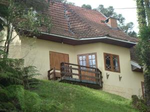 ein kleines Haus auf einem Hügel mit Balkon in der Unterkunft Chalé Suiço de Campos do Jordão in Campos do Jordão