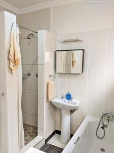 Un baño blanco con lavabo y ducha. en Home Up Guest Apartments and Lodge, en Blantyre