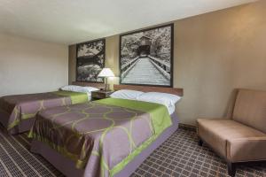 a hotel room with two beds and a chair at Super 8 by Wyndham Corvallis in Corvallis
