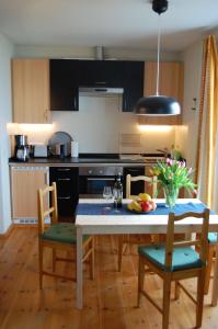 una cocina con mesa y sillas y una cocina con electrodomésticos negros en Auf dem Berg, en Malchow