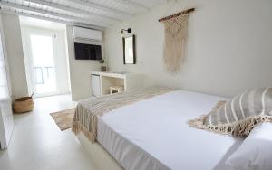 a white bedroom with a large bed and a window at Blanco Rooms Mykonos in Mikonos