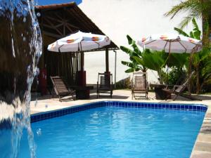 una piscina con 2 sombrillas y una fuente en Aconchego Economy, en Porto de Galinhas