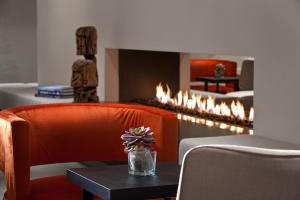 a room with a fireplace with a orange chair and a table at Wyndham Stuttgart Airport Messe in Stuttgart
