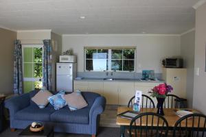 a living room with two blue couches and a kitchen at Te Mahia Bay Resort in Kenepuru Sounds