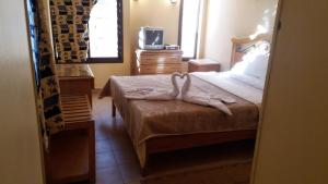 a bedroom with a bed with a dresser and a tv at Applicators Hotel in Abu Simbel