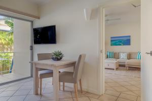 uma sala de jantar com mesa e cadeiras e uma sala de estar em Macrossan House Boutique Holiday Apartments em Port Douglas
