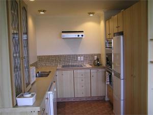 a kitchen with wooden cabinets and a white refrigerator at Terrace Apartment in Timaru