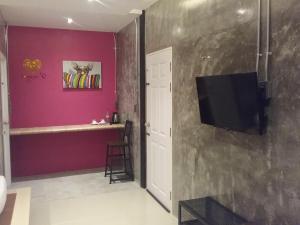 GREEN HOUSE Neo-Resotel في ناخون سي ثامارات: غرفة معيشة مع تلفزيون وجدار أرجواني