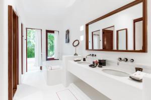 a white bathroom with two sinks and two mirrors at Hotel Esencia in Xpu Ha
