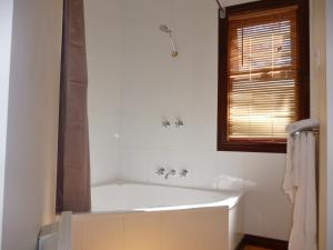 La salle de bains est pourvue d'une baignoire blanche et d'une fenêtre. dans l'établissement Tranquilles Bed & Breakfast, à Port Sorell