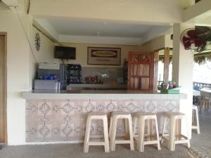 una cocina con una barra con taburetes enfrente en JoSurfInn, Puraran Beach, en Baras