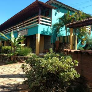 a blue building with trees and bushes in front of it at Pousada Recanto Das Pedras in Tiradentes