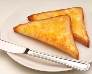 two pieces of toast on a white plate with a knife at Aurora Guest House in Wonosobo