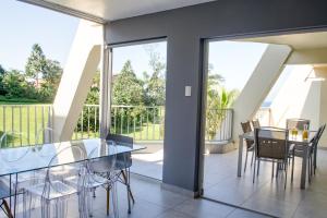 a dining room with a glass table and chairs at 14 Kyalanga - by Stay in Umhlanga in Durban