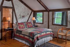 a bedroom with a bed and two windows at West Hill House B&B in Mad River Valley in Warren