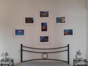 - une chambre avec un lit et des photos encadrées sur le mur dans l'établissement Campese Apartments, à Campese