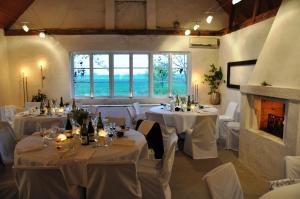 a room with white tables and white chairs and a fireplace at Borregården Bed & Breakfast in Borrby