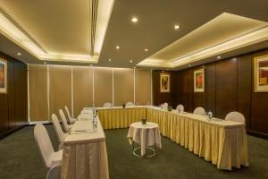 une salle de conférence avec de longues tables et des chaises blanches dans l'établissement Safir Hotel Doha, à Doha