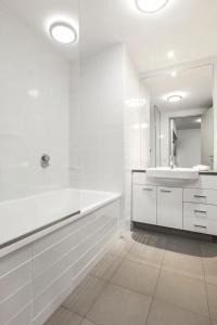 a white bathroom with a sink and a mirror at Quest at Sydney Olympic Park in Sydney