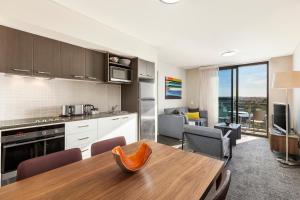 a kitchen and living room with a table and chairs at Quest at Sydney Olympic Park in Sydney