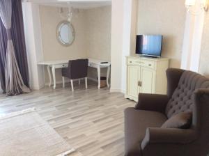 a living room with a couch and a desk with a television at Vila Royal in Urziceni