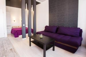 a living room with a purple couch and a bed at Sumskaya ApartHotel in Kharkiv