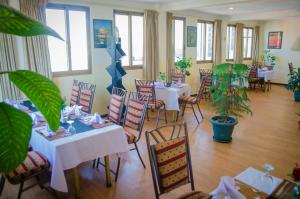 um restaurante com mesas brancas, cadeiras e plantas em Union Hotel Apartments em Addis Ababa