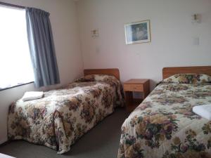 A bed or beds in a room at Ace High Motor Inn