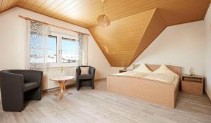 a bedroom with a bed and two chairs and a table at Pension Oppelt in Rauhenebrach