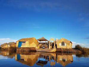 un grupo de chozas y un barco en el agua en Uros Lake Titicaca Lodge, en Puno