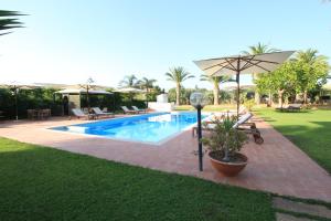 uma piscina com um guarda-sol num quintal em Villa Carlotta Resort em San Leone