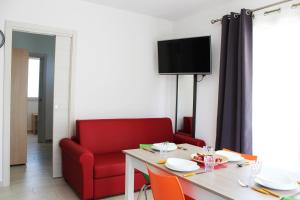 a living room with a table and a red chair at Borgo Aranci - Appartamento in Villa Orchidea - 12A in Castellammare del Golfo