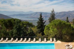 a swimming pool with chairs and a view of the mountains at Amalia Hotel Delphi in Delfoi
