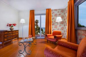 a living room with orange curtains and a couch and a table at Hotel Caparena in Taormina